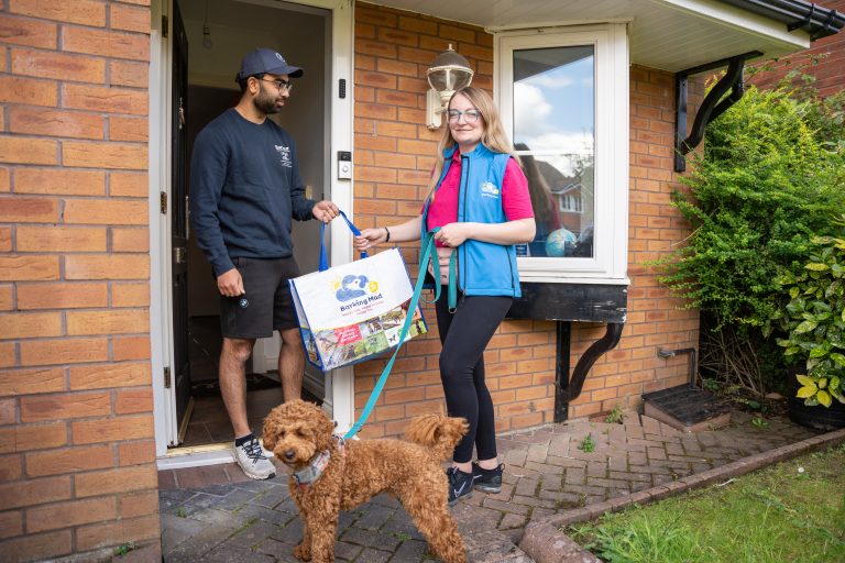 Barking Mad branch owner handing brown cockapoo over to holiday home host dog sitter