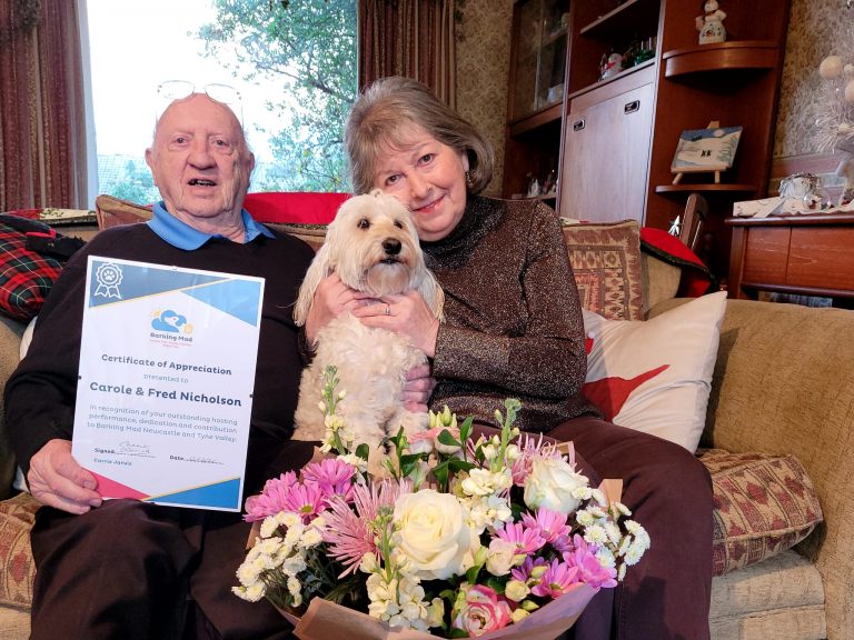 Dog Sitting hosts Carole and Fred with their dog and flowers